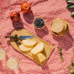Picnic al aire libre con un mantel decorativo y una variedad de alimentos sin gluten y sin alérgenos sobre la mesa.