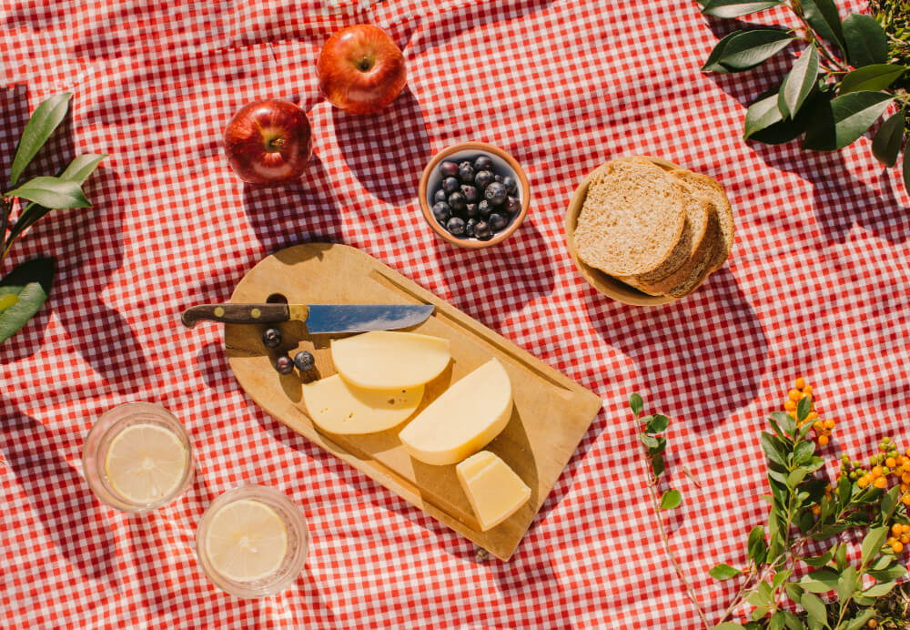 Picnic al aire libre con un mantel decorativo y una variedad de alimentos sin gluten y sin alérgenos sobre la mesa.