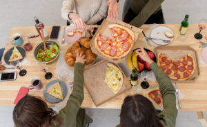 "Mesa repleta de comida variada en una reunión social, con opciones sin gluten y sin alérgenos, como pan, pasteles y aperitivos saludables.