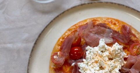 Pizza sin gluten emplatada con burrata, jamón serrano y tomates cherry sobre base Adpan