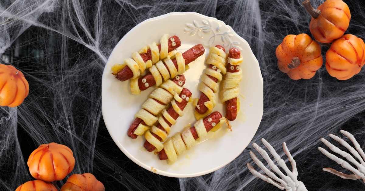 Salchimomias envueltas en masa de hojaldre sin gluten, horneadas y decoradas con ojos comestibles para Halloween.