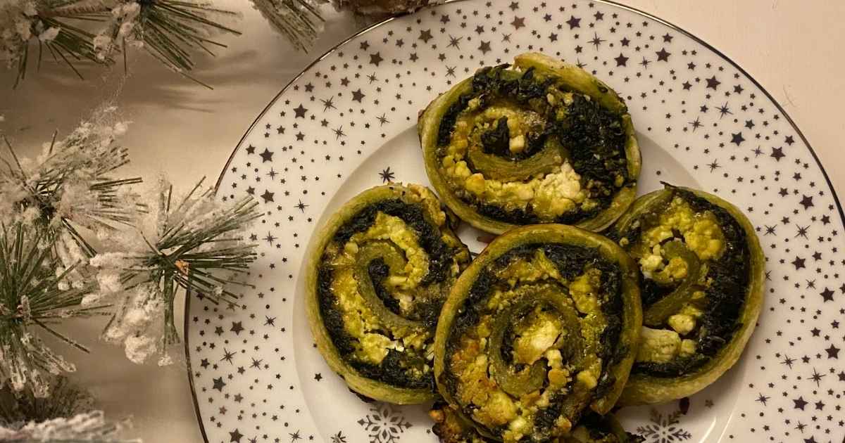 Espirales de hojaldre sin gluten con espinacas, queso feta y parmesano recién horneadas sobre una bandeja.