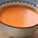 Bol de gazpacho sin gluten elaborado con tomate, pepino, pimiento rojo, pimiento verde y pan sin gluten ADPAN, servido frío.